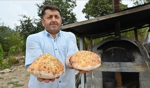 İmam taş fırında pişirdiği ekmekleri köylülere ikram ediyor